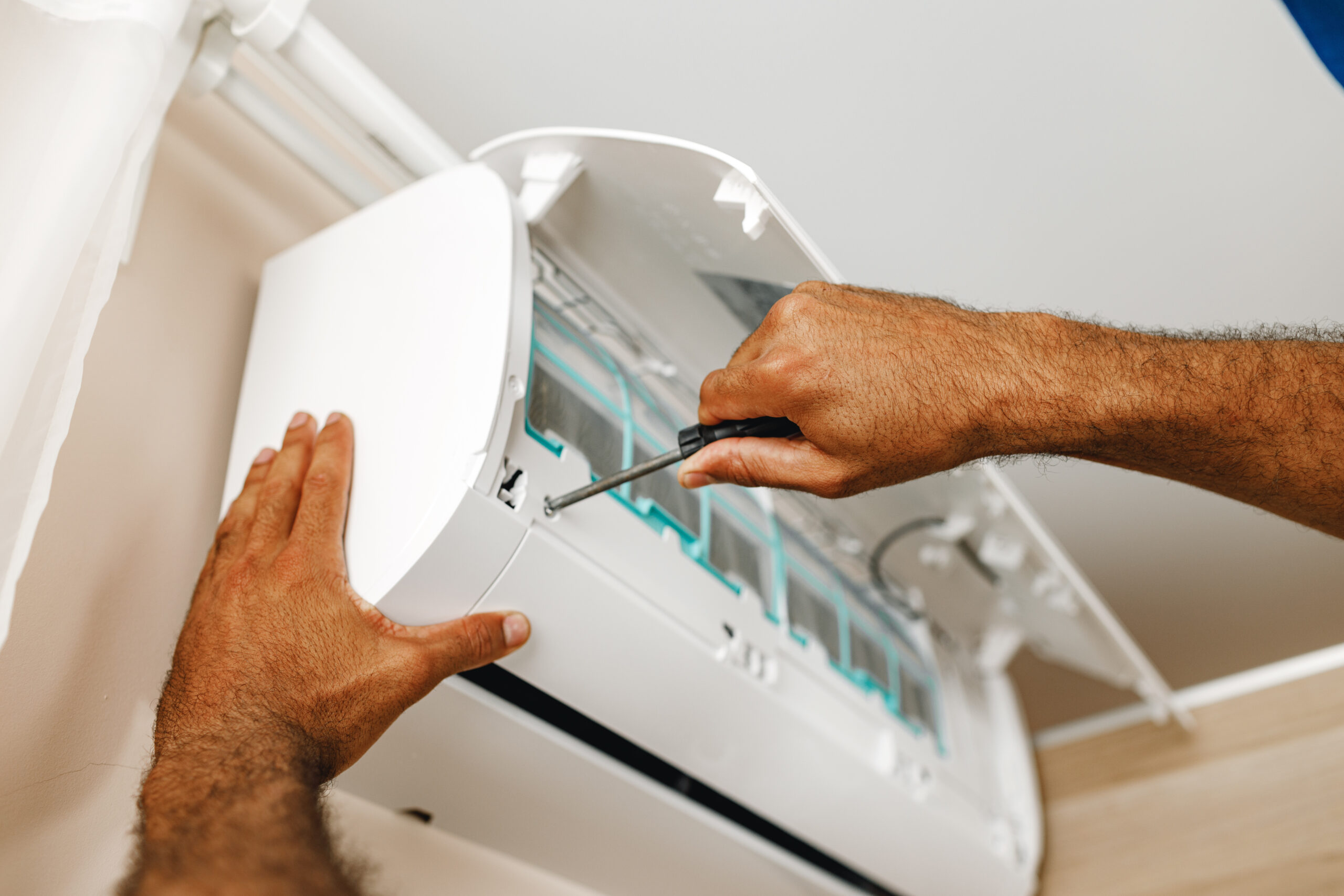 Close up photo of repairman fixing air conditioner in a room
